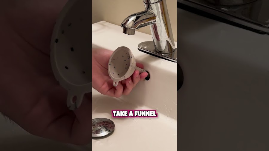 A person holds a small funnel up to the overflow hole of a white bathroom sink beneath a chrome faucet during 1-Tom-Plumber service.
